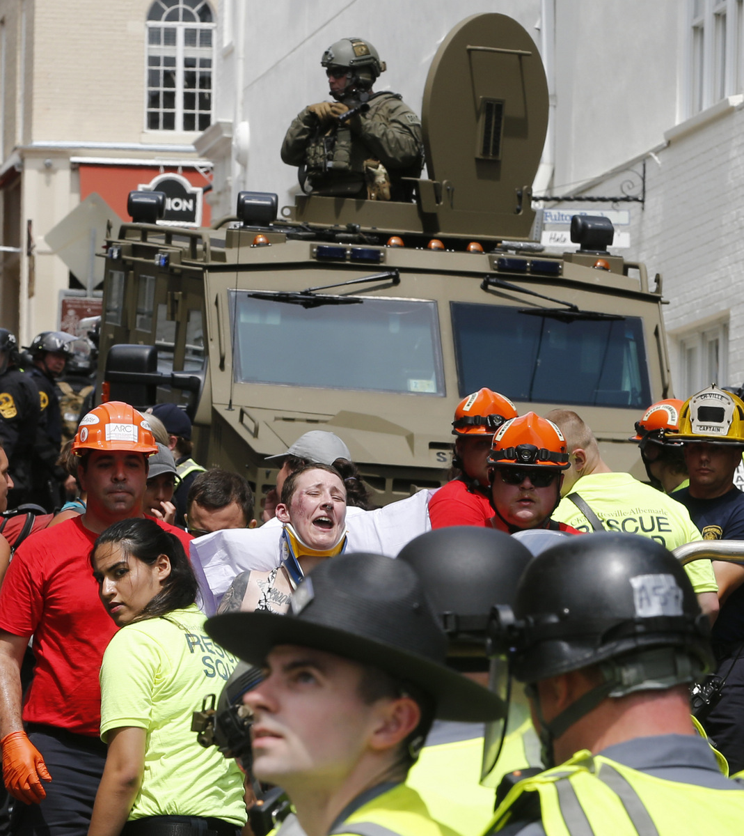 Rescue personnel help injured people while police patrol in armored vehicles after a car ran into a large group of protesters after an white nationalist rally in Charlottesville, Va., Aug. 12, 2017. (AP/Steve Helber)