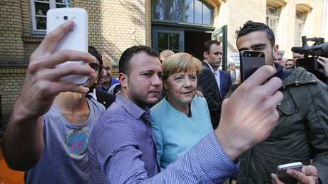 Migrants from Syria and Iraq take selfies with German Chancellor Angela Merkel outside a refugee camp near the Federal Office for Migration and Refugees after their registration at Berlin's Spandau district, Germany, September 10, 2015. © Fabrizio Bensch