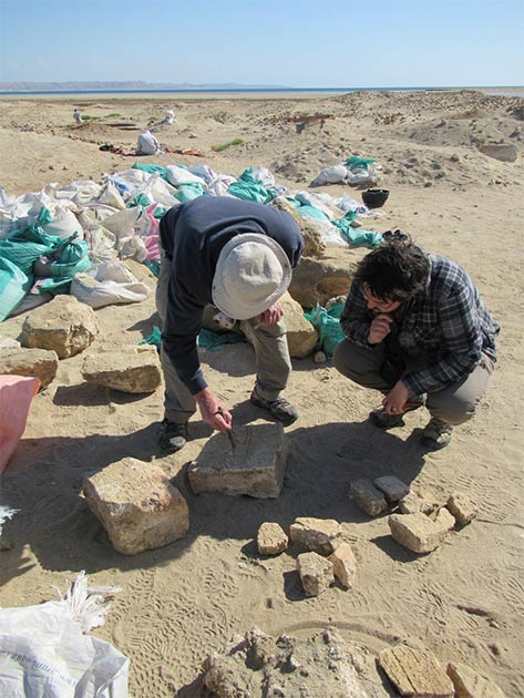 Archaeologists examine a block carved with hieroglyphs at the site. (I. Zych / PAP)