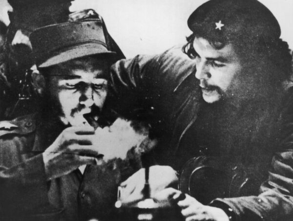 Cuban revolutionary Fidel Castro (left) lights his cigar while Argentine revolutionary Che Guevara (1928-1967) looks on in the early days of their guerrilla campaign in the Sierra Maestra Mountains of Cuba, circa 1956. Castro wears a military uniform while Guevara wears fatigues and a beret. (Hulton Archive/Getty Images)