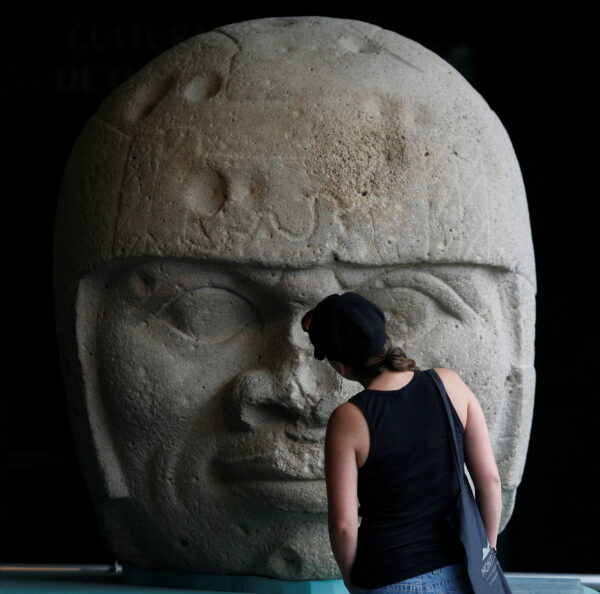 Visitor looks at an Olmec colossal head during the preview of "Colossal masterworks of the Olmec world" exhibition at the Anthropology Museum in Mexico City