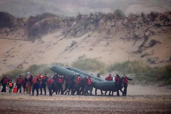 A group of more than 40 migrants run through the Slack dunes with an inflatable dinghy, to leave the coast of northern France and to cross the English Channel, near Wimereux, France, on Wednesday.