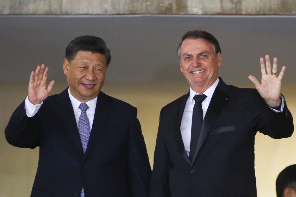 China's President Xi Jinping (L) and Brazil's President Jair Bolsonaro (R) wave before a bilateral meeting ahead of the 11th edition of the BRICS Summit, on November 13, 2019. - Brazil's President Jair Bolsonaro walked a diplomatic tightrope, as he seeks to boost ties with Beijing and avoid upsetting key ally Donald Trump, on the eve of a summit with their BRICS counterparts from Russia, India and South Africa. (Photo by Sergio LIMA / AFP) (Photo by SERGIO LIMA/AFP via Getty Images)