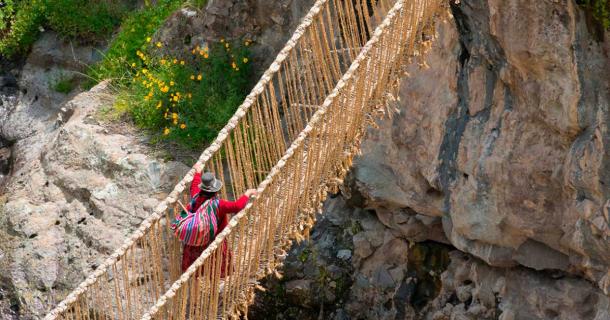 Woman crossing the Queshuachaca Inca rope bridge near Huinchiri in Peru. Source: Danita Delimont / Adobe Stock