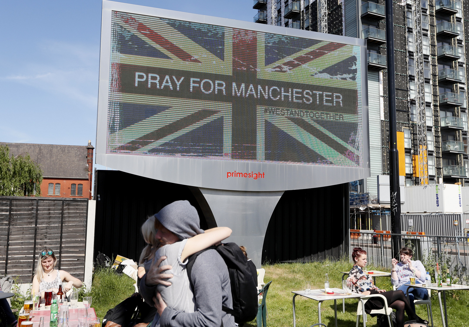 A couple embrace under a billboard in Manchester city centre, Tuesday May 23, 2017, the day after the suicide attack at an Ariana Grande concert that left 22 people dead as it ended on Monday night. (AP/Kirsty Wigglesworth)