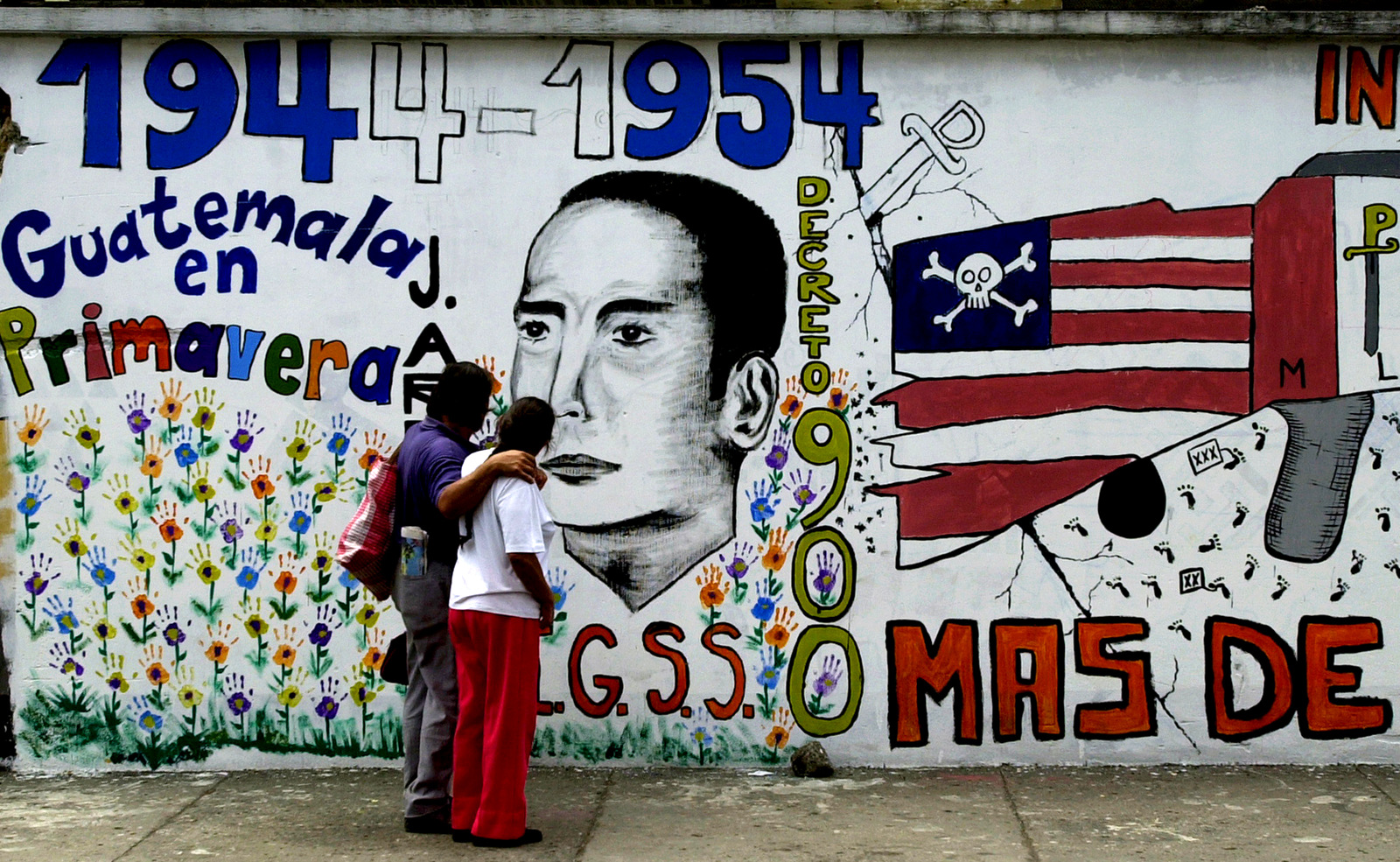 A couple walks by a mural in downtown Guatemala City commemorating the 50th anniversary of a CIA backed military intervention that ousted leftist president Jacobo Arbenz in Guatemala. (AP/Rodrigo Abd)