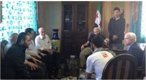 Photo of U.S. Senator John McCain meeting illegally in a rebel safe house with the heads of the “Free Syrian Army” in Idlib, Syria in April, 2013. In the left foreground, top al Qaeda terrorist leader Ibrahim al-Badri (aka Al-Baghdadi of ISIS, a.k.a. Caliph Ibrahim of the recently founded Islamic State with whom the Senator is talking. Behind Badri is visible Brigadier General Salim Idris (with glasses), the former military chief of the FSA, who has since fled to the Gulf states after the collapse of any semblance of the FSA.