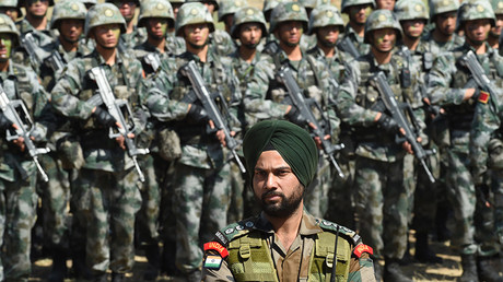 FILE PHOTO: An Indian Army soldier stands in front of a group of People's Liberation Army of China soldiers © Indranil Mukherjee