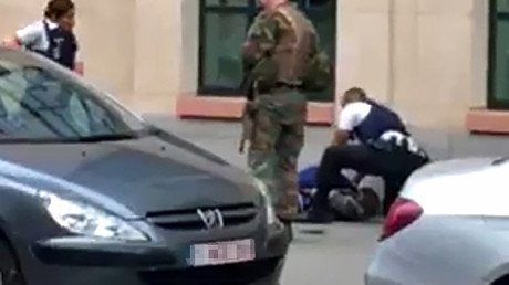 This screengrab shows police officials and a soldier looking at a man on the pavement in the city centre of Brussels on August 25, 2017, where a man is alleged to have attacked soldiers with a knife and was shot. © AFP

