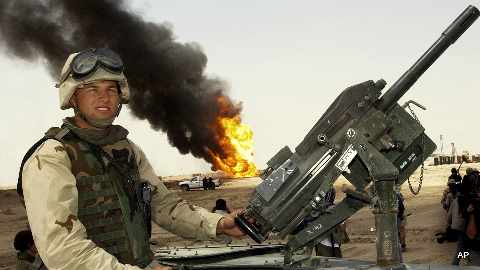 In this April 1, 2003 file photo, a U.S. soldier stands guard on top of a humvee as oil workers work on oil well fires at Rumaila oil field, southern Iraq.