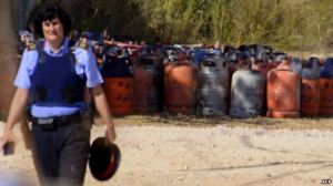 A policewoman walks with dozen of gas bottles in background in Alcanar during a search linked to the Barcelona and Cambrils attacks on the site of an explosion on August 18, 2017. 