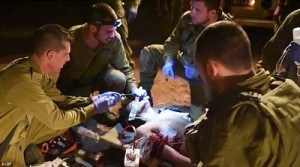 A wounded Syrian Islamic militant receives urgent medical treatment from Israeli troops at the Syrian border. The commandos are seen administering 'tracheal intubation' by forcing a tube down the man's throat to prevent asphyxiation. Click to enlarge
