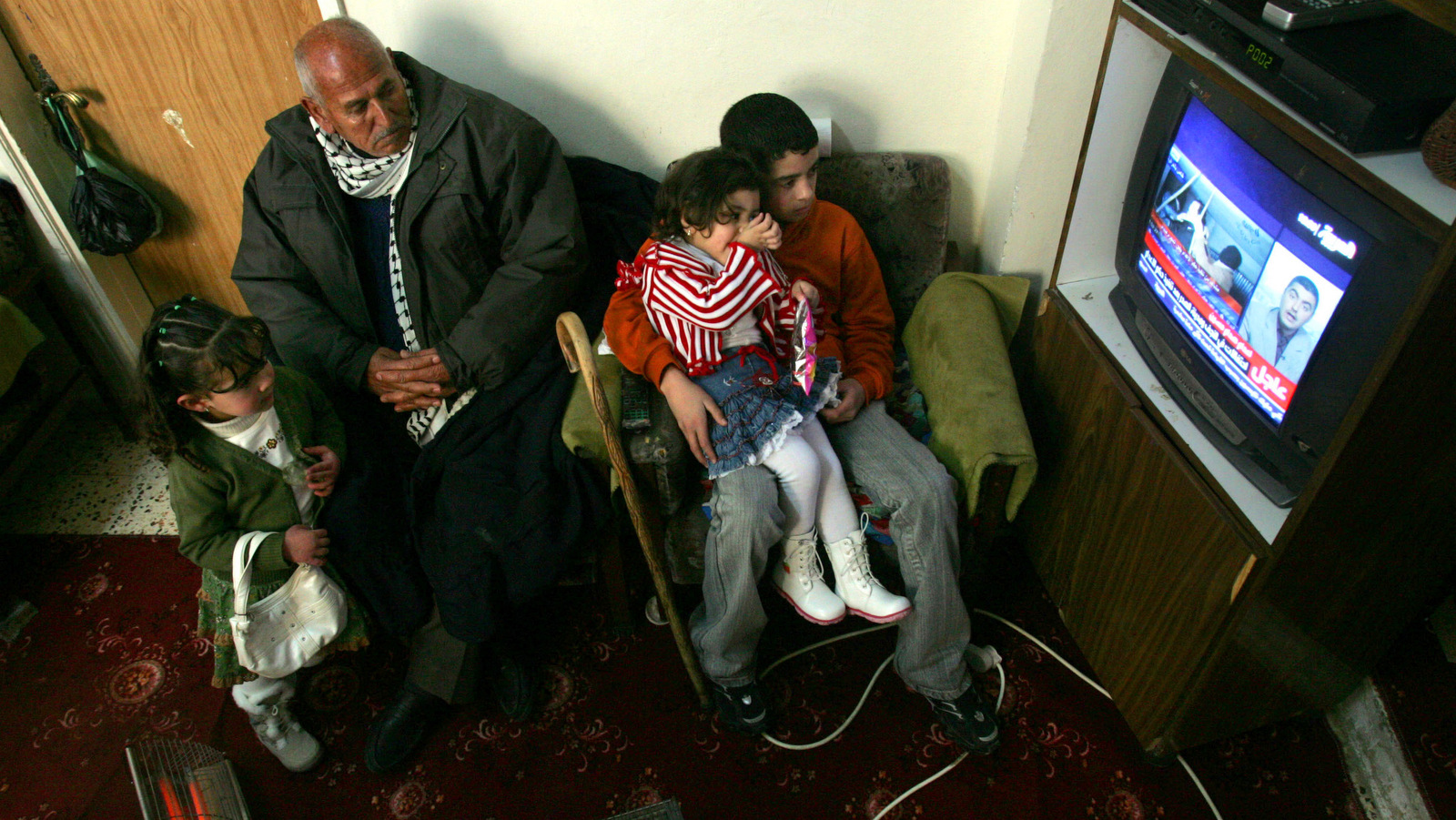 A Palestinian family watches Saudi state-owned Al-Arabiya TV transmitting a video of the execution of Saddam Hussein, in the West Bank town of Ramallah, Dec. 30, 2006. (AP/Muhammed Muheisen)