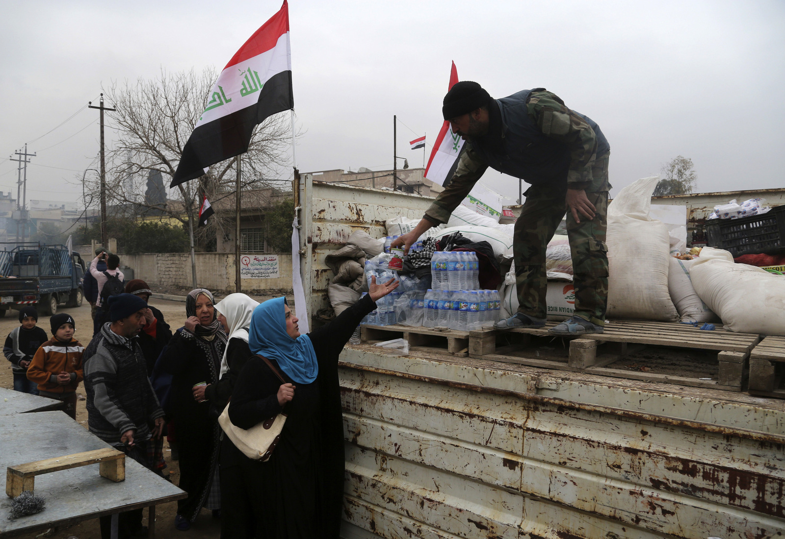 Shiite volunteer fighters of the Popular Mobilization Forces (Hashd al-Shaabi) distribute food to the residents in a neighborhood recently liberated from ISIS militants, on the eastern side of Mosul, Iraq, Jan. 15, 2017.(AP/Khalid Mohammed)