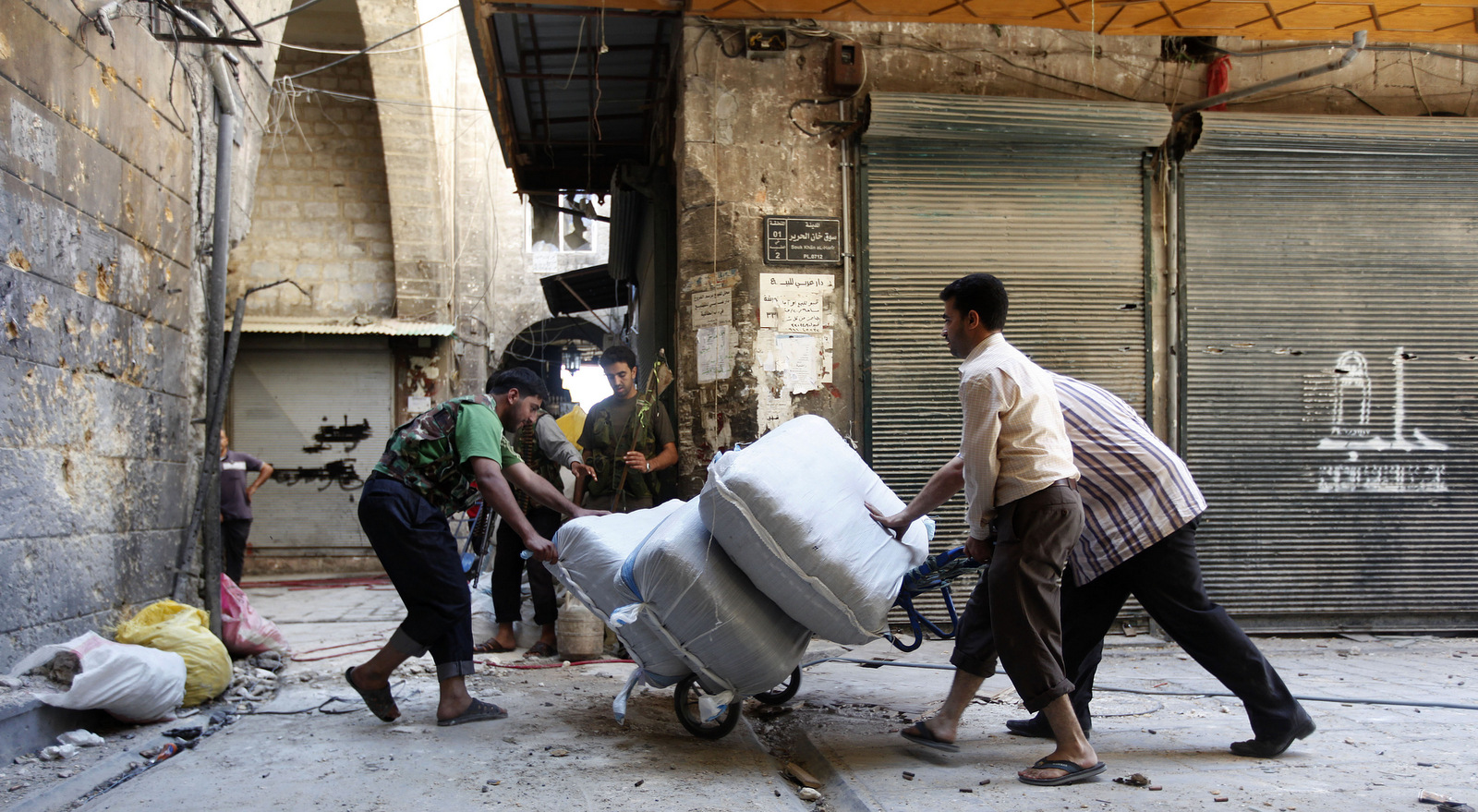 A Free Syrian Army fighter moves supplies at the souk of the old city of Aleppo city, Syria, September 24, 2012. The Arabic on the closed shop at right reads: "Aleppo." (AP/Hussein Malla)