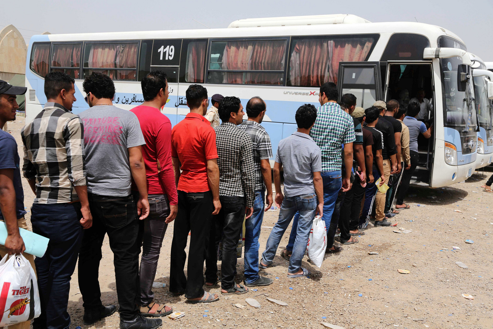 Iraqi men line up to board a bus at a recruiting center to volunteer with the popular mobilization units (Hashd al-Shaabi) to fight ISIS insurgents, Baghdad, Iraq, June 20, 2014. (AP/Karim Kadim)
