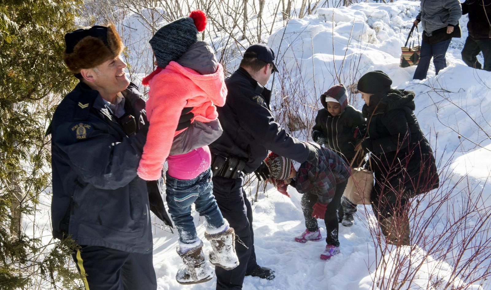 Family members are helped into Canada by Royal Canadian Mounted Police officers along the U.S.-Canada border near Hemmingford, Quebec. (Canadian Press via AP)