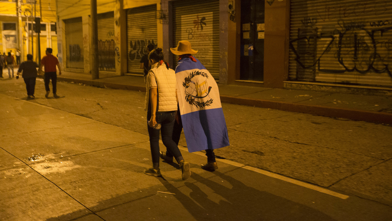 A protester with a Guatemalan flag over his shoulders walks away from Congress in Guatemala City, Jan. 16, 2017. after an extraordinary session ended, where Lawmakers repealed a recently passed bill that reduced the punishment for illegal campaign financing. Riot police dispersed the protesters with batons and pepper spray. (AP/Moises Castillo)