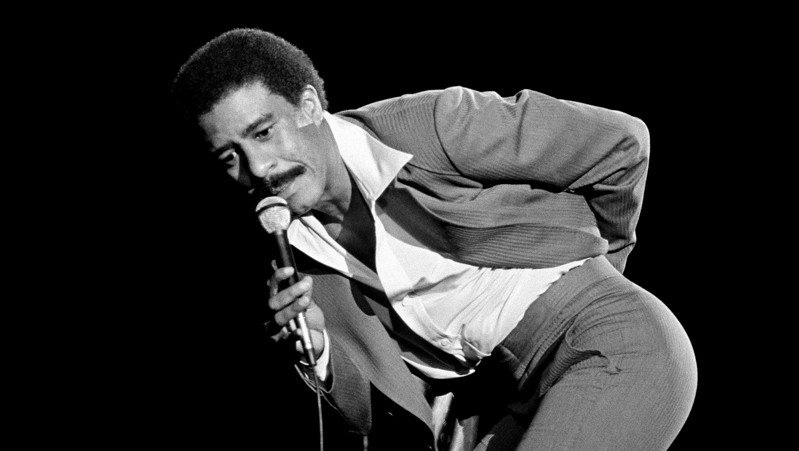 Comedian Richard Pryor gestures to the audience, after the audience jeered him for his remarks at a gathering billed as A Star Spangled Night for Rights, Sept. 19, 1977, Hollywood Bowl, Los Angeles, Calif. After the gesture, Pryor slammed the mike down and left the show. (AP/Lennox McLendon)