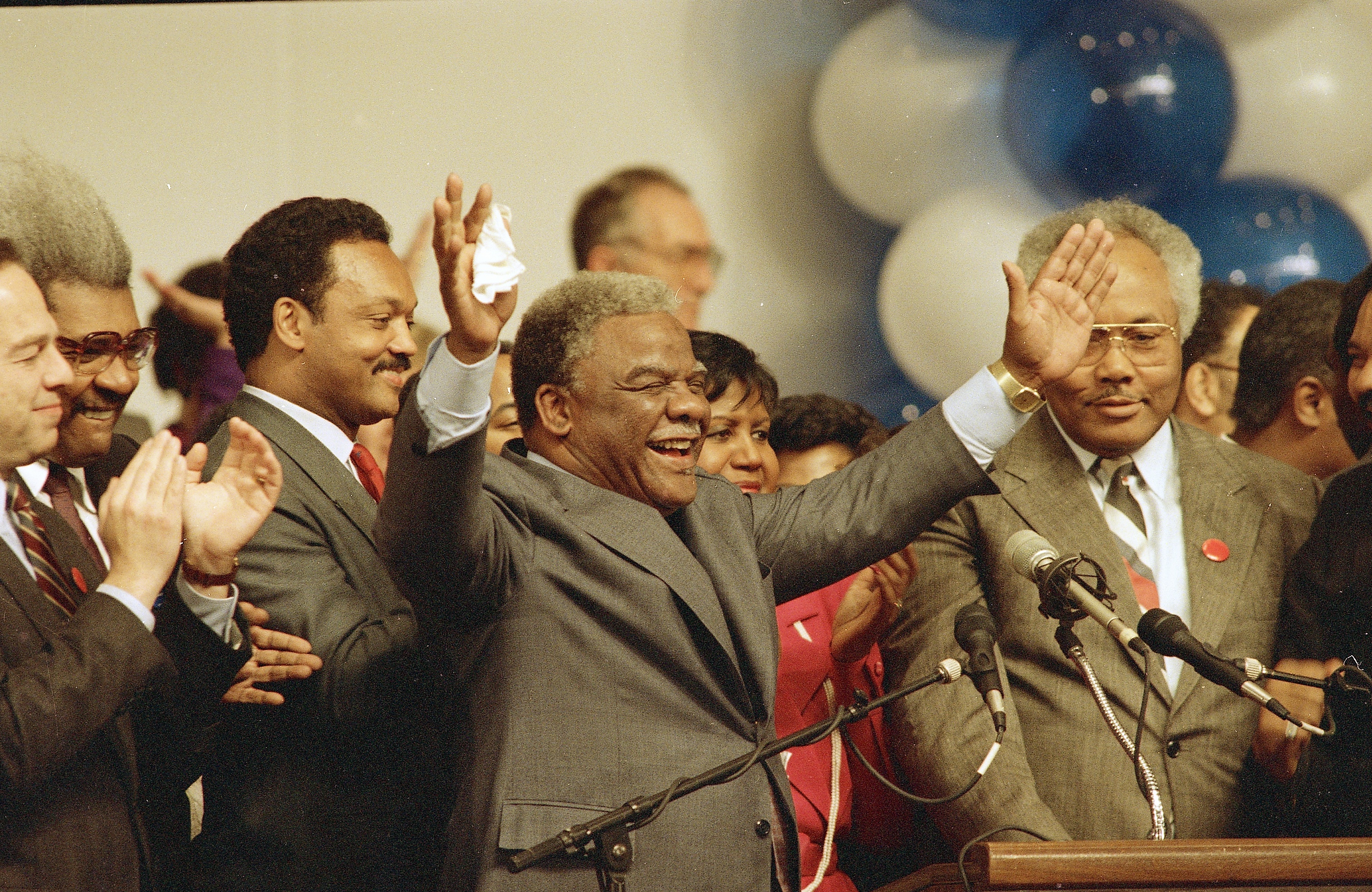 Harold Washington waves to cheering supporters as he announced victory in his bid for re-election as mayor of Chicago. At left is Rev, Jesse Jackson, April 7, 1987. (AP/Fred Jewell)