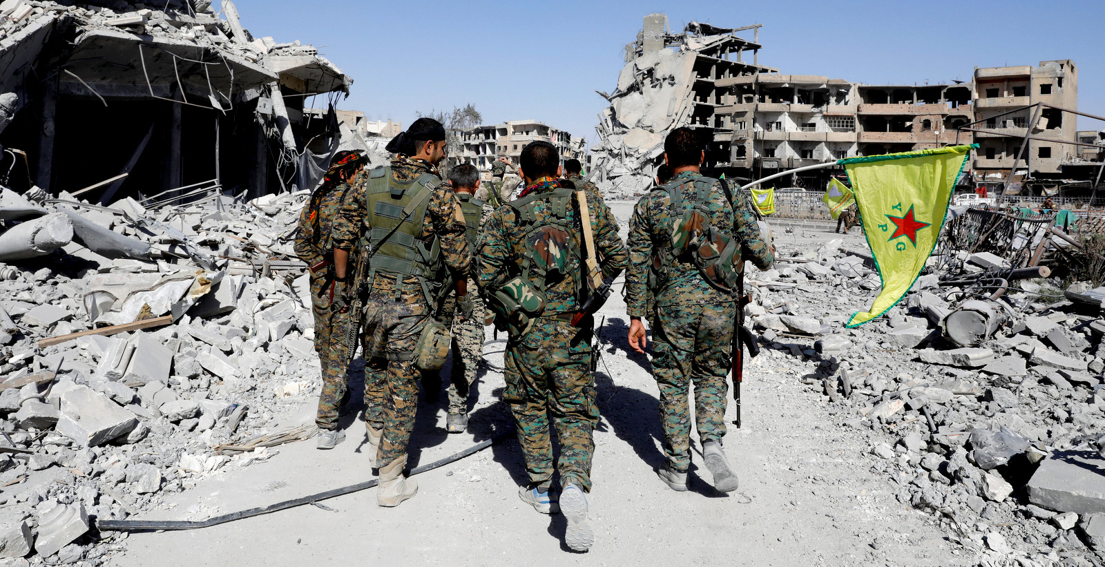 Syrian Democratic Forces Fighters walk past the ruins of destroyed buildings near the National Hospital after Raqqa was liberated from the Islamic State (ISIS), in Raqqa, Syria October 17, 2017. (Erik De Castro/Reuters)