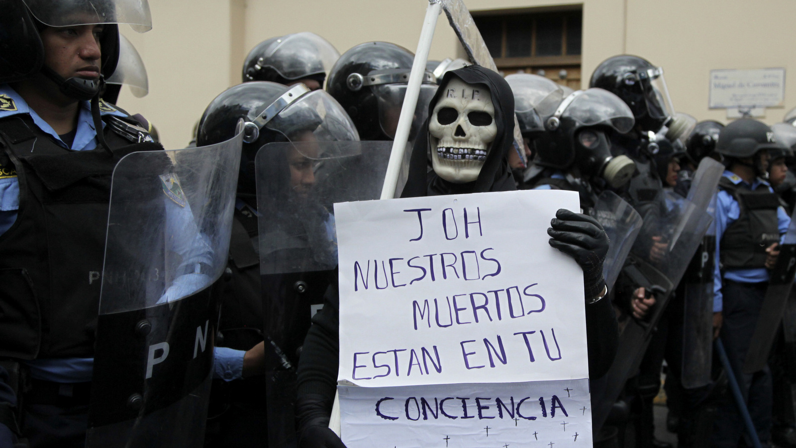 A protester wearing a grim reaper costume holds a sign with a message that reads in Spanish: "JOH our dead are on your conscience," during a protest by demonstrators against Honduras' President Juan Orlando Hernandez, in Tegucigalpa, Honduras, Jan. 25, 2018. Hernandez was awarded the electoral win last month despite the disputed vote tally. The opposition plans to continue protesting through his swearing-in Jan. 27. (AP/Fernando Antonio)