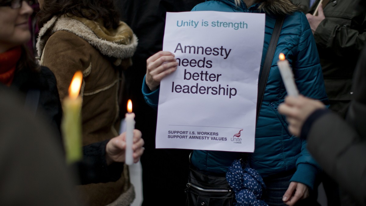 People hold candles and a placard as they take part in a picket outside Amnesty International offices in London, Tuesday, Nov. 20, 2012. Amnesty International workers in London walked off the job on Tuesday as the second strike in as many months raised questions about the organization's ability to remain one of the world's pre-eminent human rights advocates. (AP Photo/Matt Dunham)