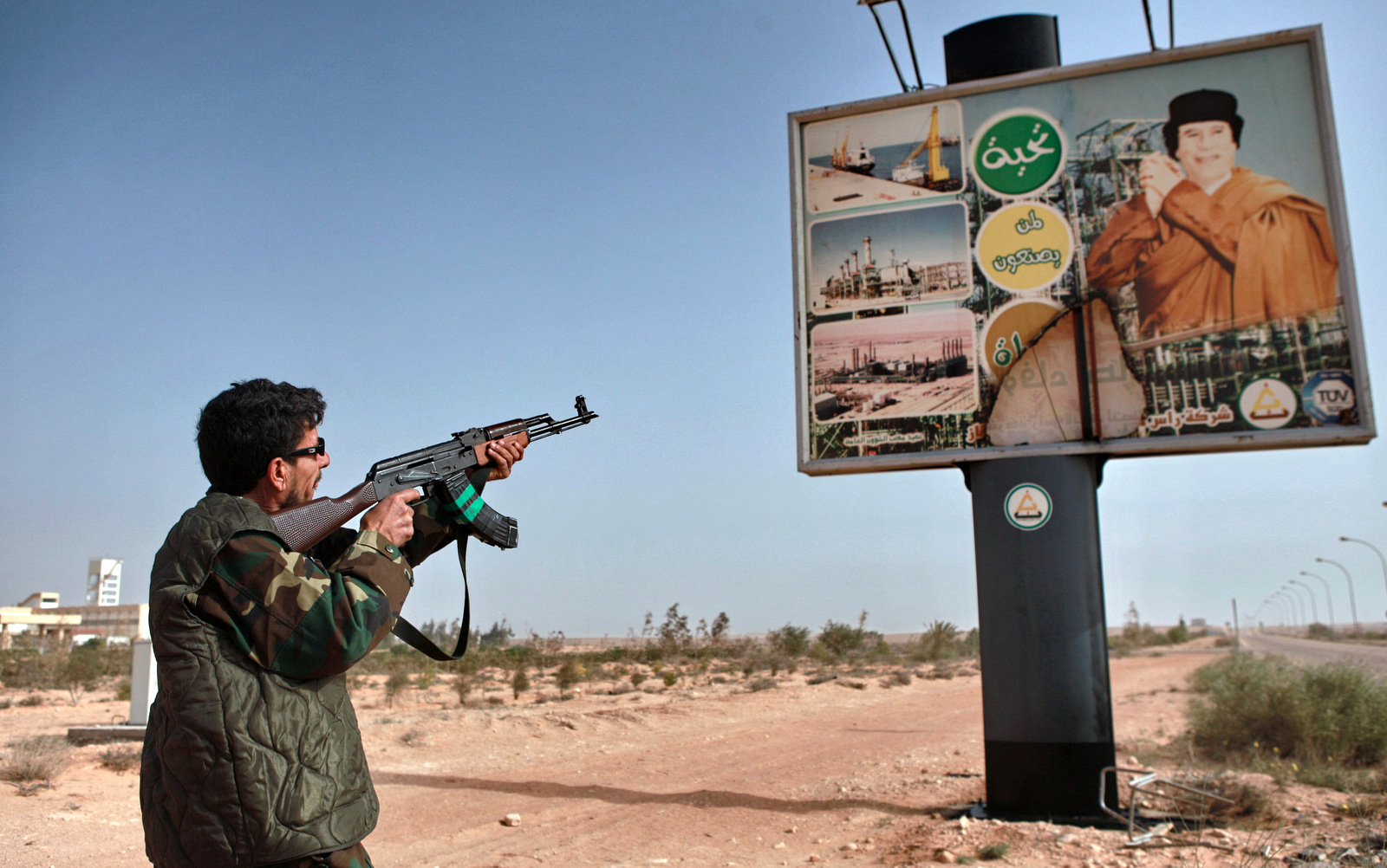 An armed Libyan rebel shoots an AK-47 at a poster of Muhammar Gaddafi in the captured rebel town of Ras-Lanuf in the east of the country (Photo: Andrey Stenin/Sputnik)