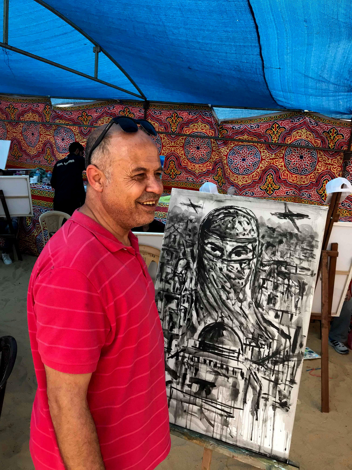 Basel el-Maqosui stands in front of his one of his paintings. (Photo: Shareef Sarhan)