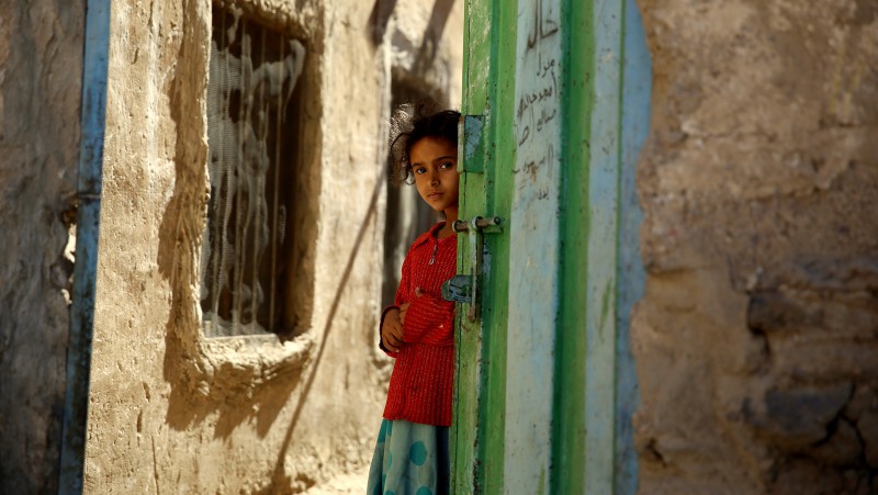 A girl stands in a doorway as she watches children receiving a polio vaccination, during a house-to-house polio immunization campaign in Sanaa, Yemen. Monday, Nov. 9, 2015. A national three-day anti-Polio immunization campaign to vaccinate more than 5 million children across Yemen began on Monday. (AP Photo/Hani Mohammed)