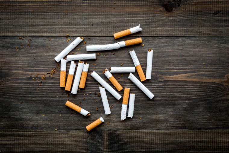 Tobacco. Scattered cigarettes on dark wooden background top view copy space