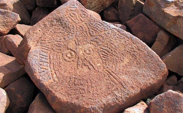 The enigmatic archaic faces, found in large numbers over the Burrup are among the earliest rock art works in the region. This may be one of the oldest carved faces in the world (Image: Ken Mulvaney)