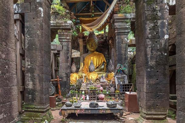 Clothed statues of the Buddha seated, table with stones and Buddhist relics, at the center of Vat Phou Temple. (Basile Morin / CC BY-SA 4.0)