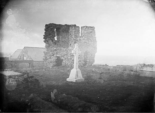 Abbey ruins with graves and Celtic cross memorial, circa 1885. 