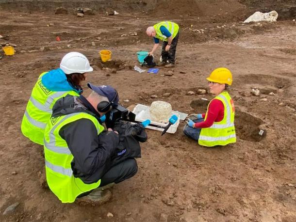 Susannah Kelly (on the right), a specially trained archaeological conservator, showing RTE reporters the successful removal of the urn from the earth and clay it was surrounded by. (Fadó Archaeology)