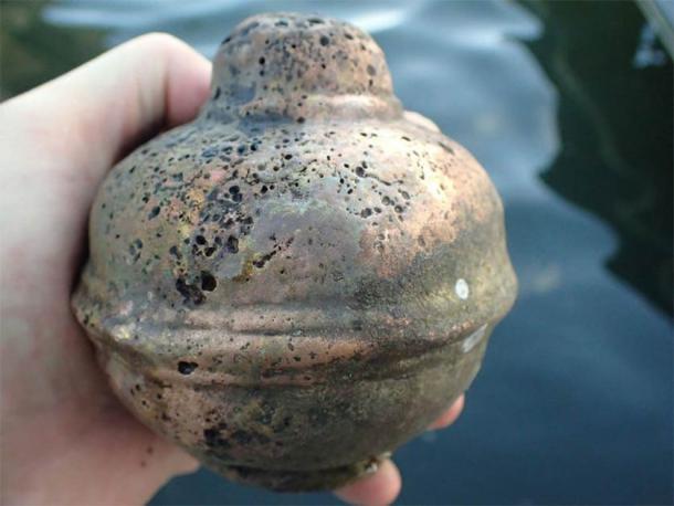 The sunken Danish warship shows signs of a violent fire. Amongst the artifacts retrieved from the shipwreck, were pieces of bronze cannons (left) and a calculation coin (right). (Morten Johansen / The Viking Ship Museum)
