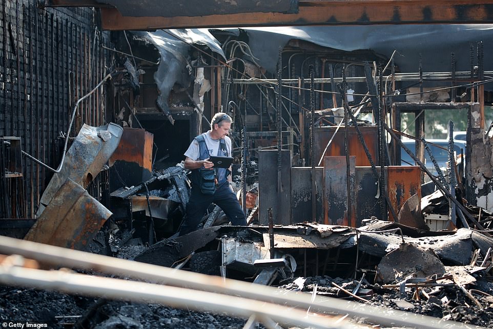 An ATF agent collects evidence in a burned out store that was destroyed during riots on Thursday in Kenosha. Protests devolving into violence have left countless buildings charred, businesses looted and destroyed, and streets littered with debris as Kenosha emerged as the latest flashpoint in a summer of US demonstrations against police brutality and racism