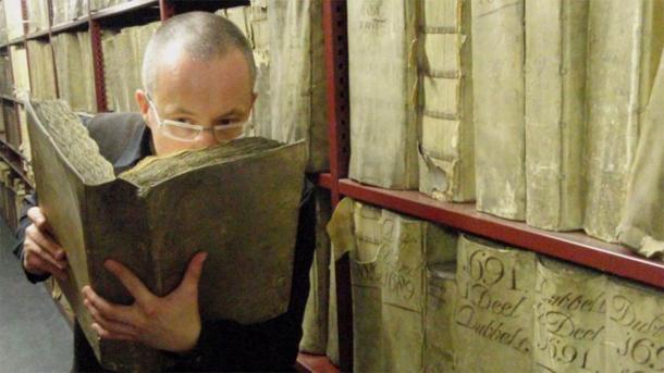 An AI robot will be used to scan historic texts and paintings as parte of the Odeuropa project, which aims to create a smell encyclopedia and recreate smells of the past. In the image Professor Matija Strlic smells an ancient text in the National Archives of The Netherlands. (Matija Strlic / Odeuropa)
