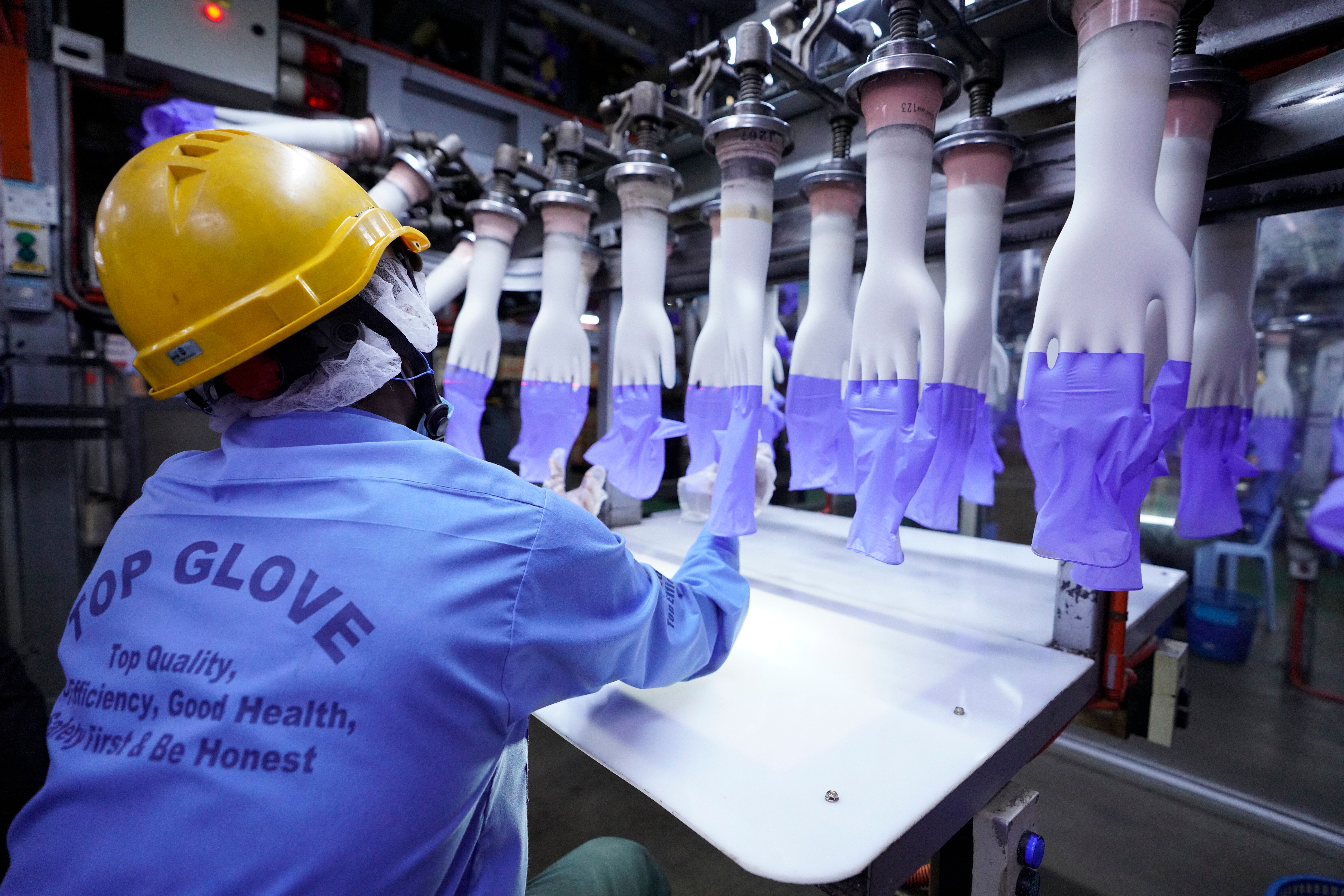 In this Aug. 26 file photo, a worker inspects disposable gloves at the Top Glove factory in Shah Alam on the outskirts of Kua