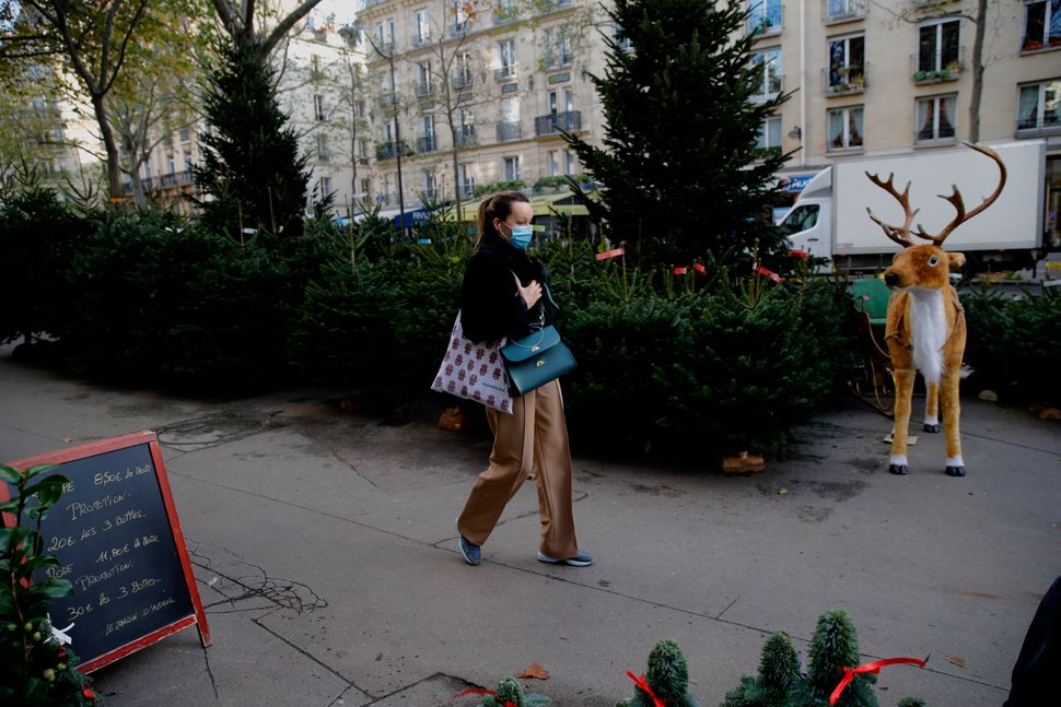 A woman walks past Christmas trees at florist in Paris on Friday. The number of new coronavirus infections in France rose by 