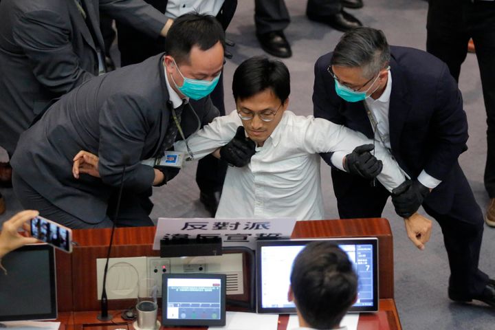 Then pan-democratic legislator Eddie Chu, center, is taken away by security guards during a Legislative Council's House Commi