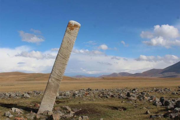 A leaning Deer Stone placed in front of dozens of small stone mounds containing ritually-sacrificed horse burials at the Bronze Age monument site of Ikh Tsagaanii Am, Bayankhongor Province, central Mongolia. (William Taylor)