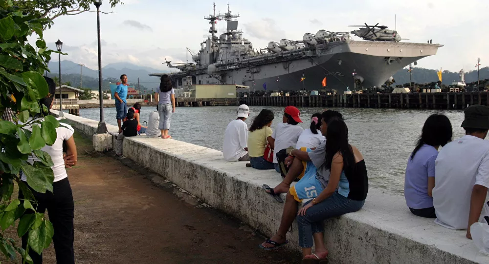 People stand near the docked amphibious assault ship USS Essex at Subic Bay, Philippines.