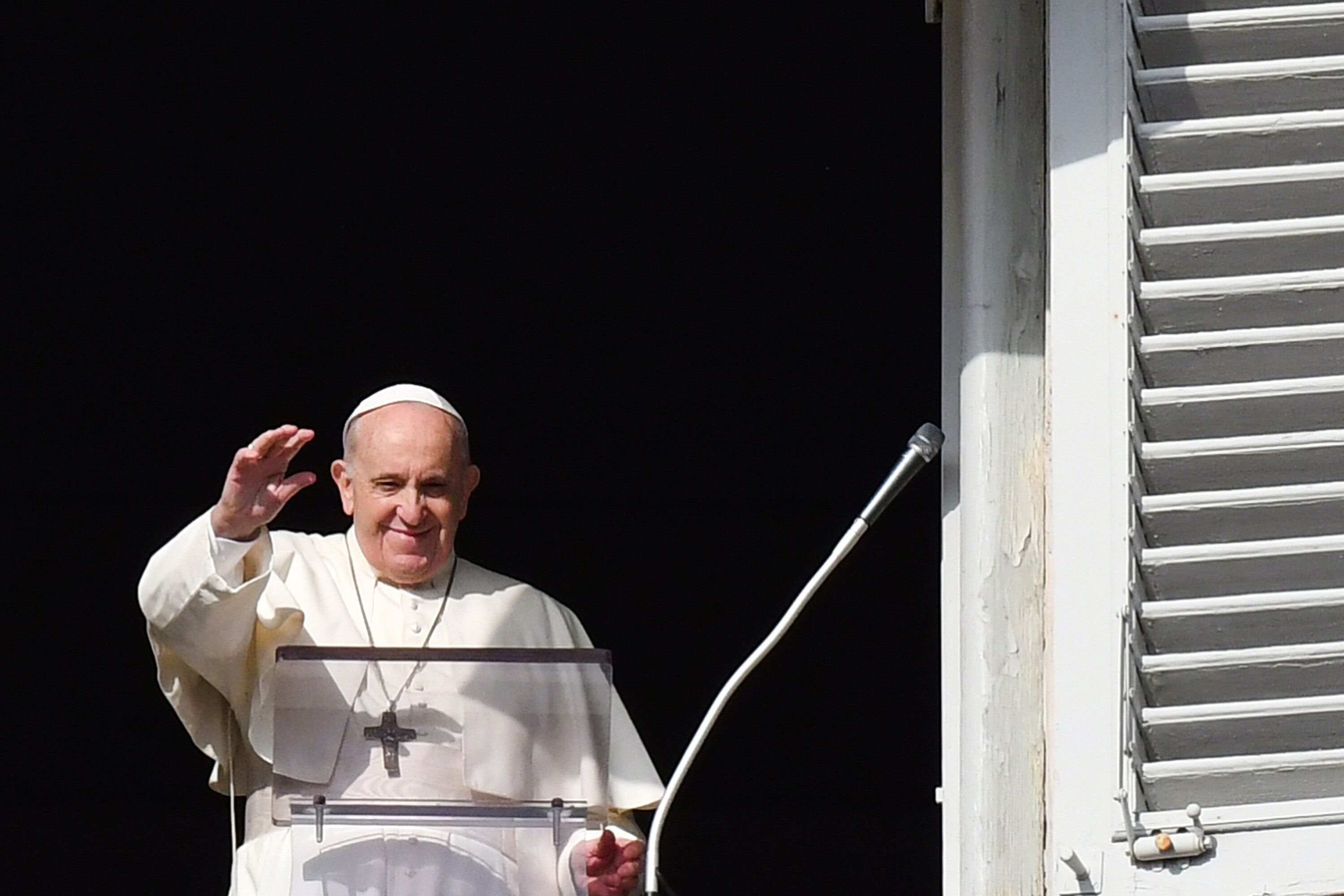 Pope Francis waves as he addresses the crowd from a window overlooking St Peter's Square during his weekly Angelus prayer at 