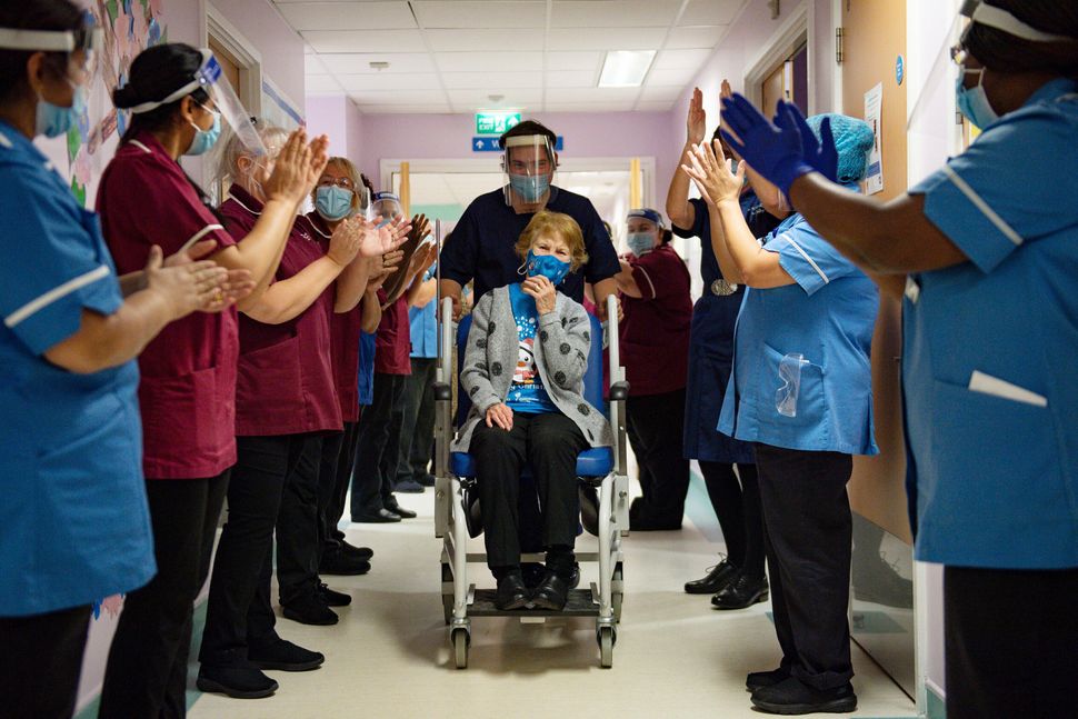 Margaret Keenan, 90, receives applause from staff as she returns to her ward after becoming the first patient in the world to