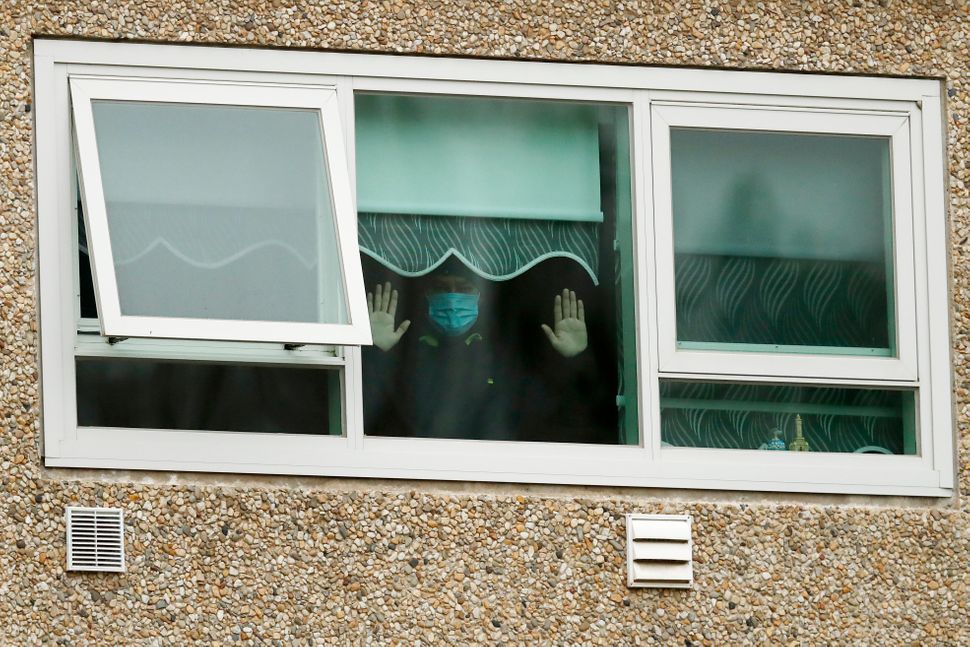 A man looks out the window of the Flemington Towers government housing complex on July 6 in Melbourne, Australia. Nine public