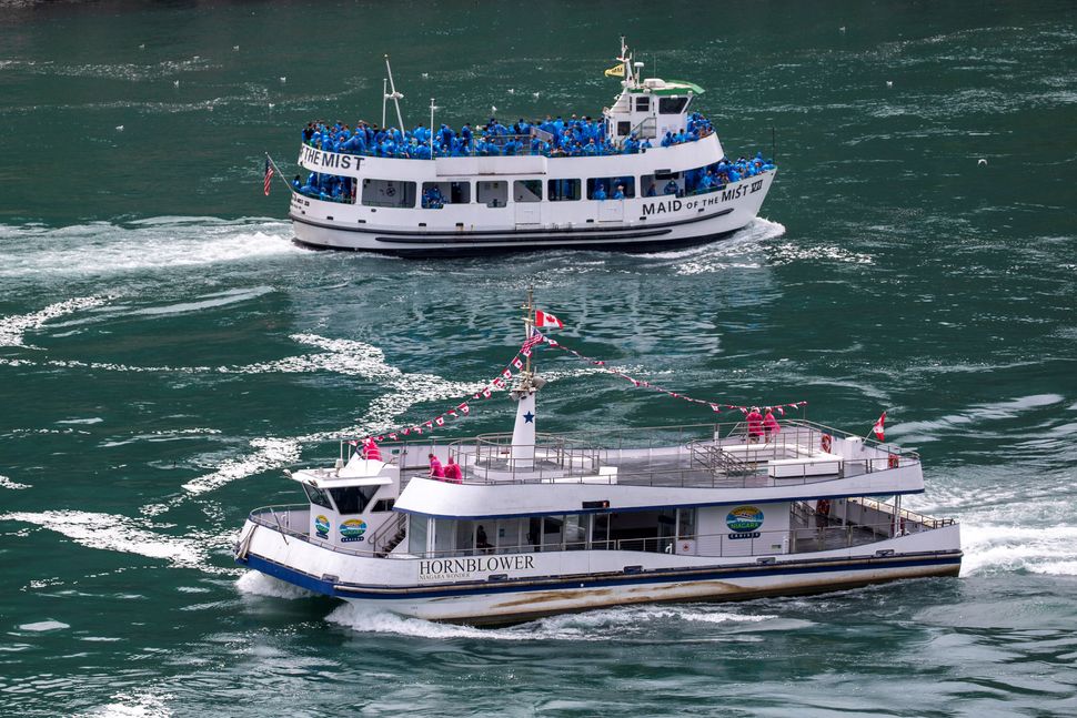 American tourist boat Maid of the Mist, limited to 50% occupancy under New York State rules, glides past a Canadian vessel li