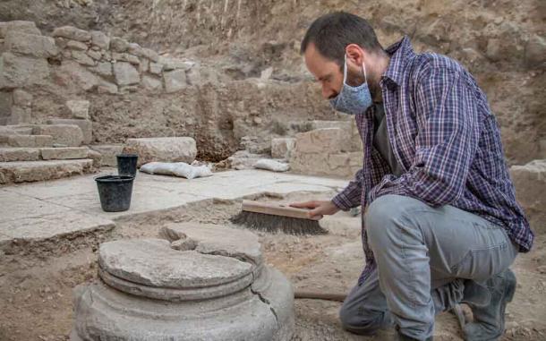 An archaeologist cleaning one of the pillar bases upon which the 1,500-year-old Byzantine church was built. The church was found in the garden area before the ritual bathes were discovered. (Yoli Schwarz / Israel Antiquities Authority)