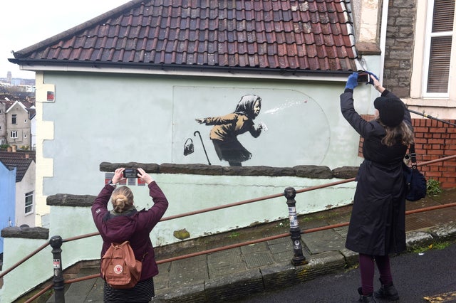 People take pictures of a new street artwork entitled 'Aachoo!!' by Banksy in Totterdown, Bristol