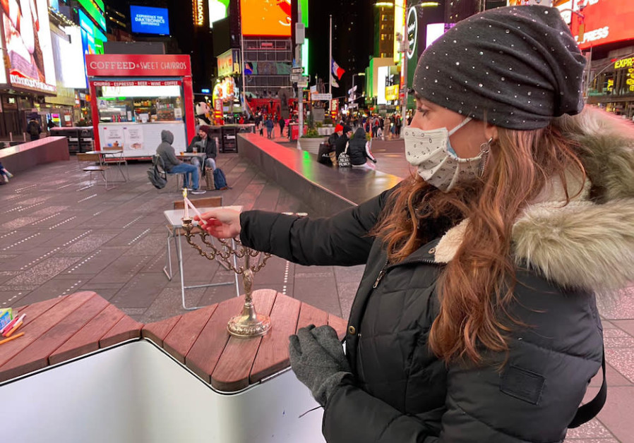 A woman lights a Hanukkah menorah in New York's Time Square. (THE JEWISH AGENCY FOR ISRAEL)
